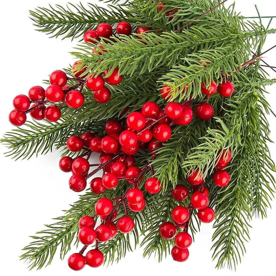 Artificial green pine sprigs with glossy red berries, close-up