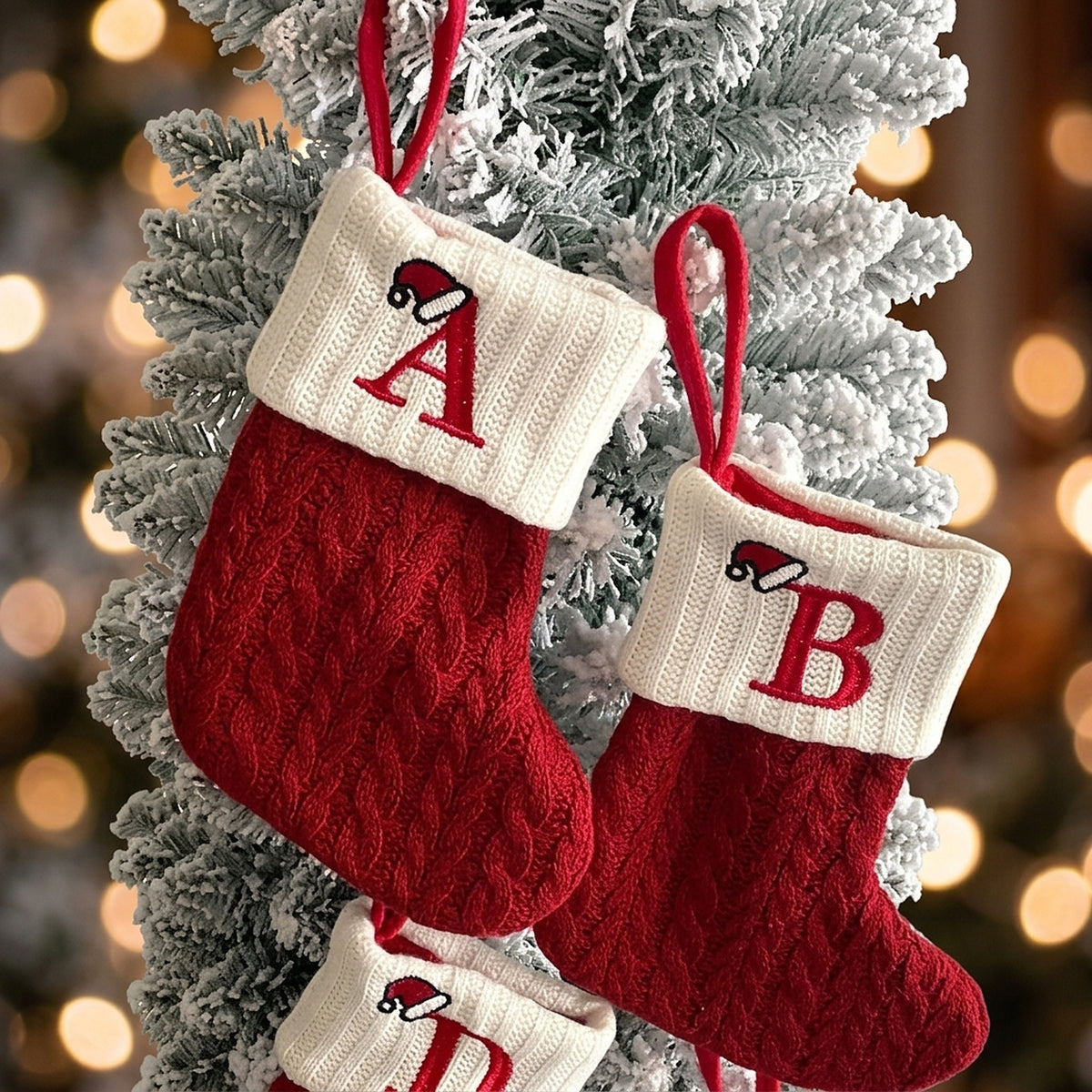 Mini knit stockings with letters A and B hanging on a snowy tree