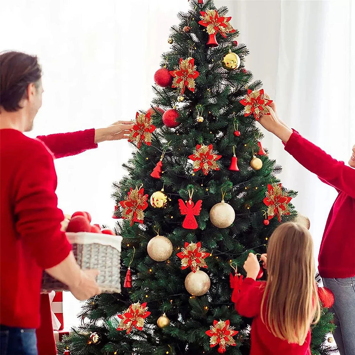 Family decorating a tree with red glitter poinsettias