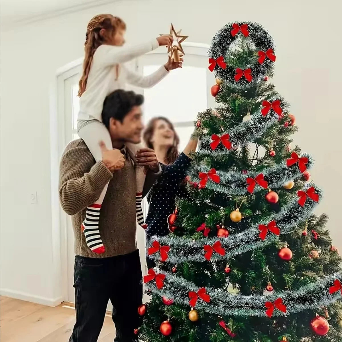 Family decorating a Christmas tree with tinsel garland and red bows