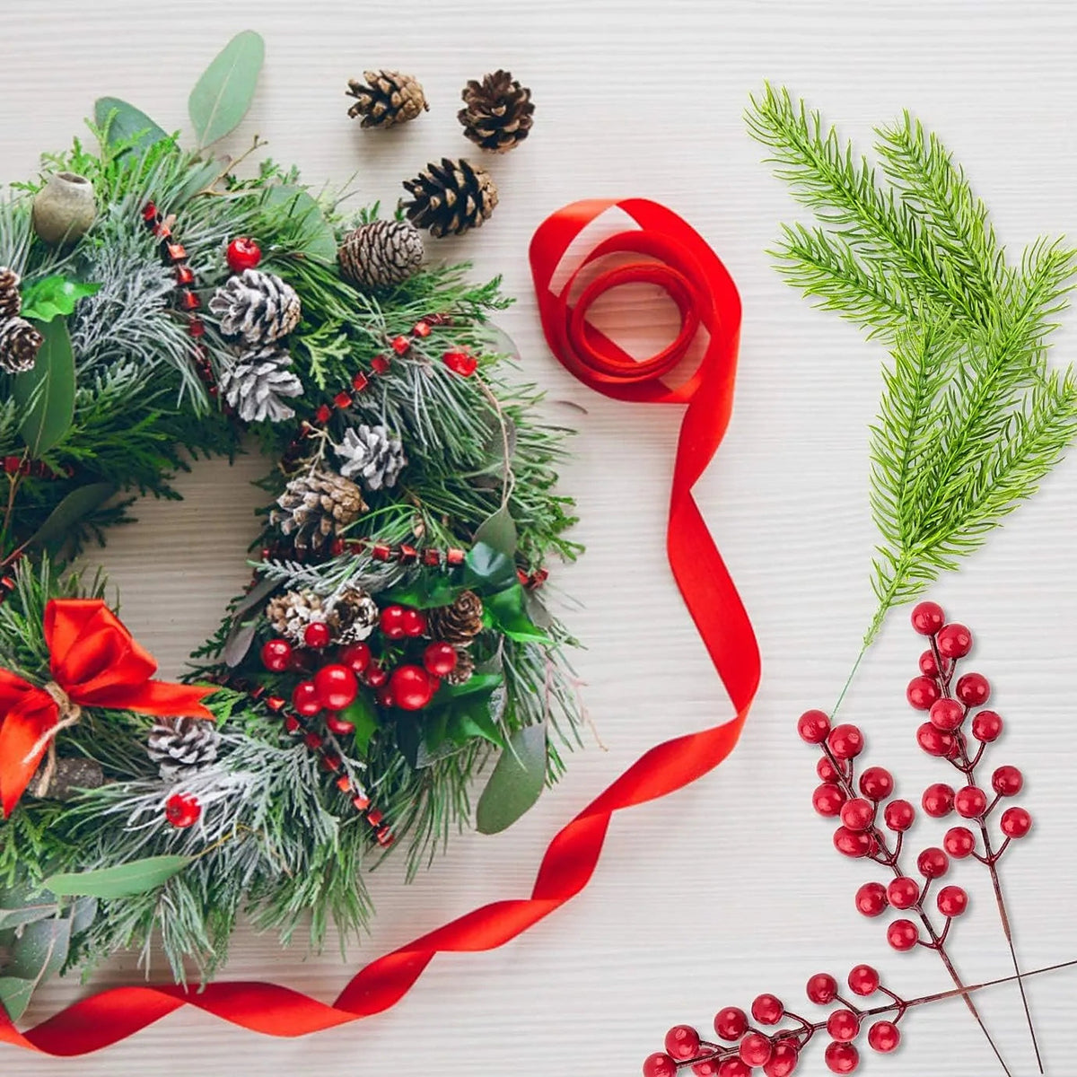 Pine and red berry picks next to a wreath and red ribbon