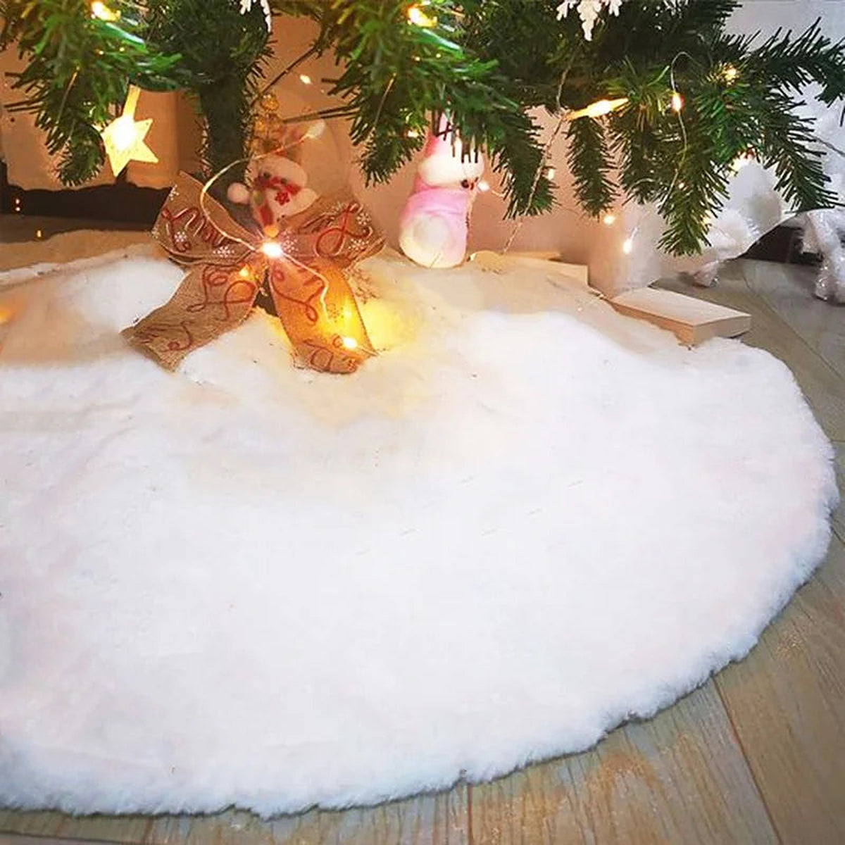 White plush tree skirt under a lit tree