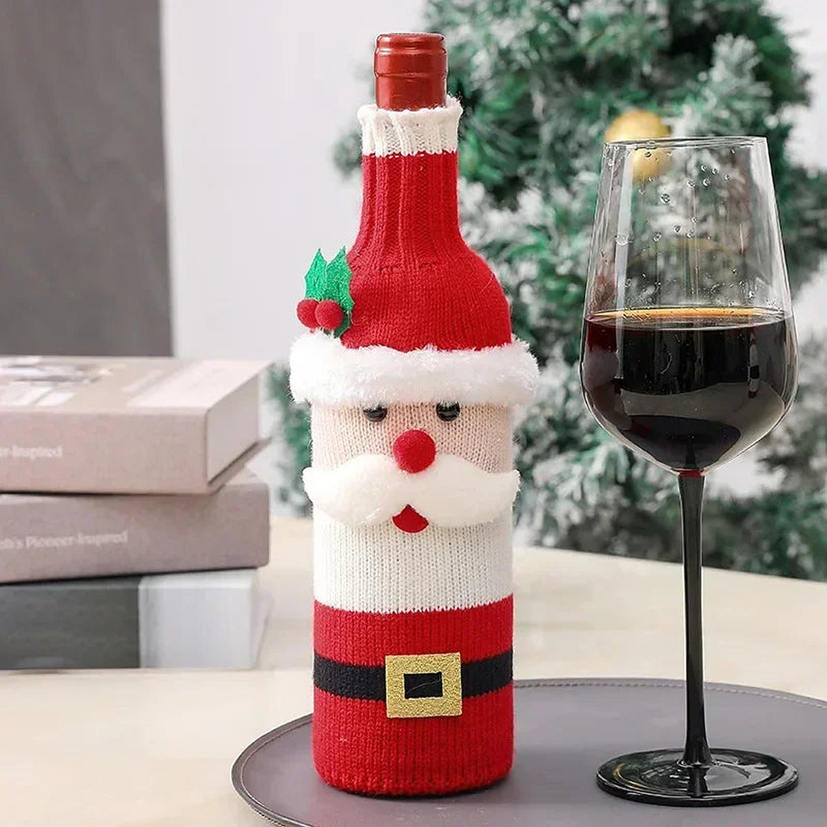 Santa knit wine bottle cover beside a glass of wine